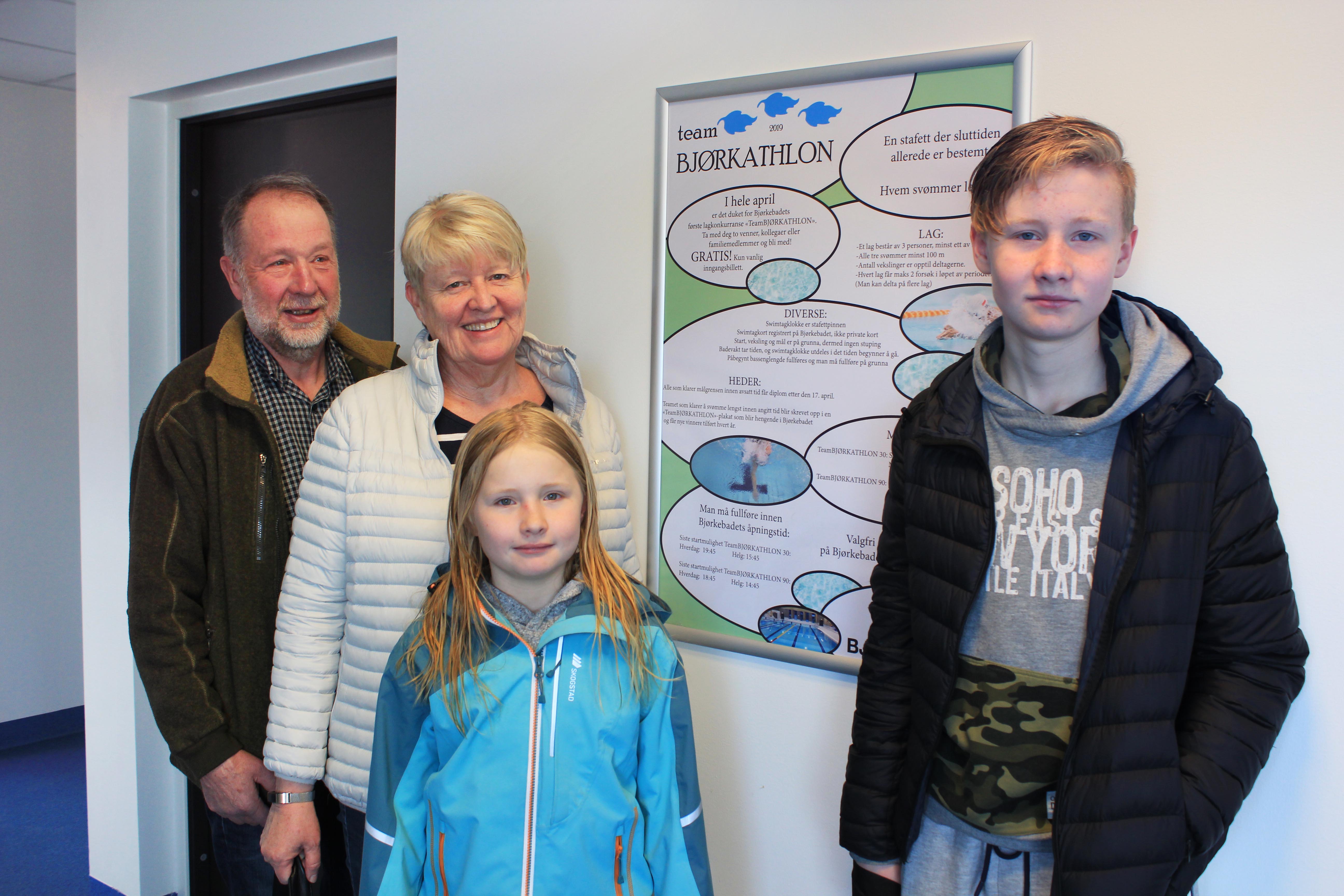 Stokkebekk besteforeldre og barnebarn foran TeamBjørkathlon plakat