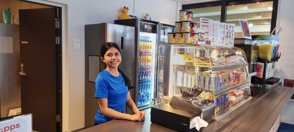 Lærling står i kassen ved kafeen i Bjørkebadet